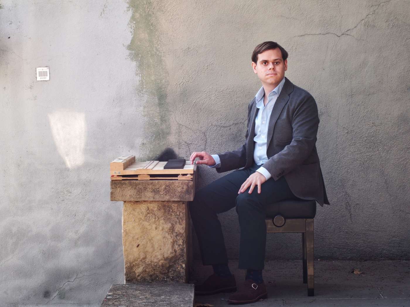 Ignasi Cambra seated at a keyboard against a weathered wall